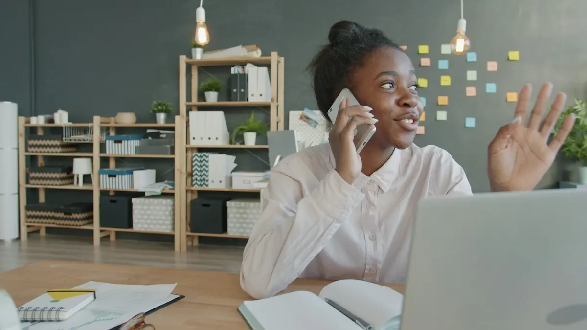Une jeune femme au téléphone, devant son ordinateur portable
