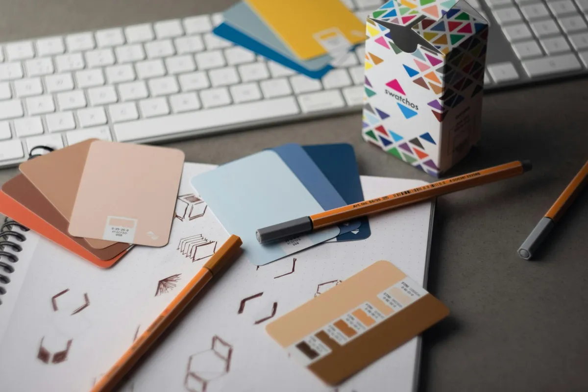 Un bureau de designer : croquis de logos, nuancier de couleurs et crayons